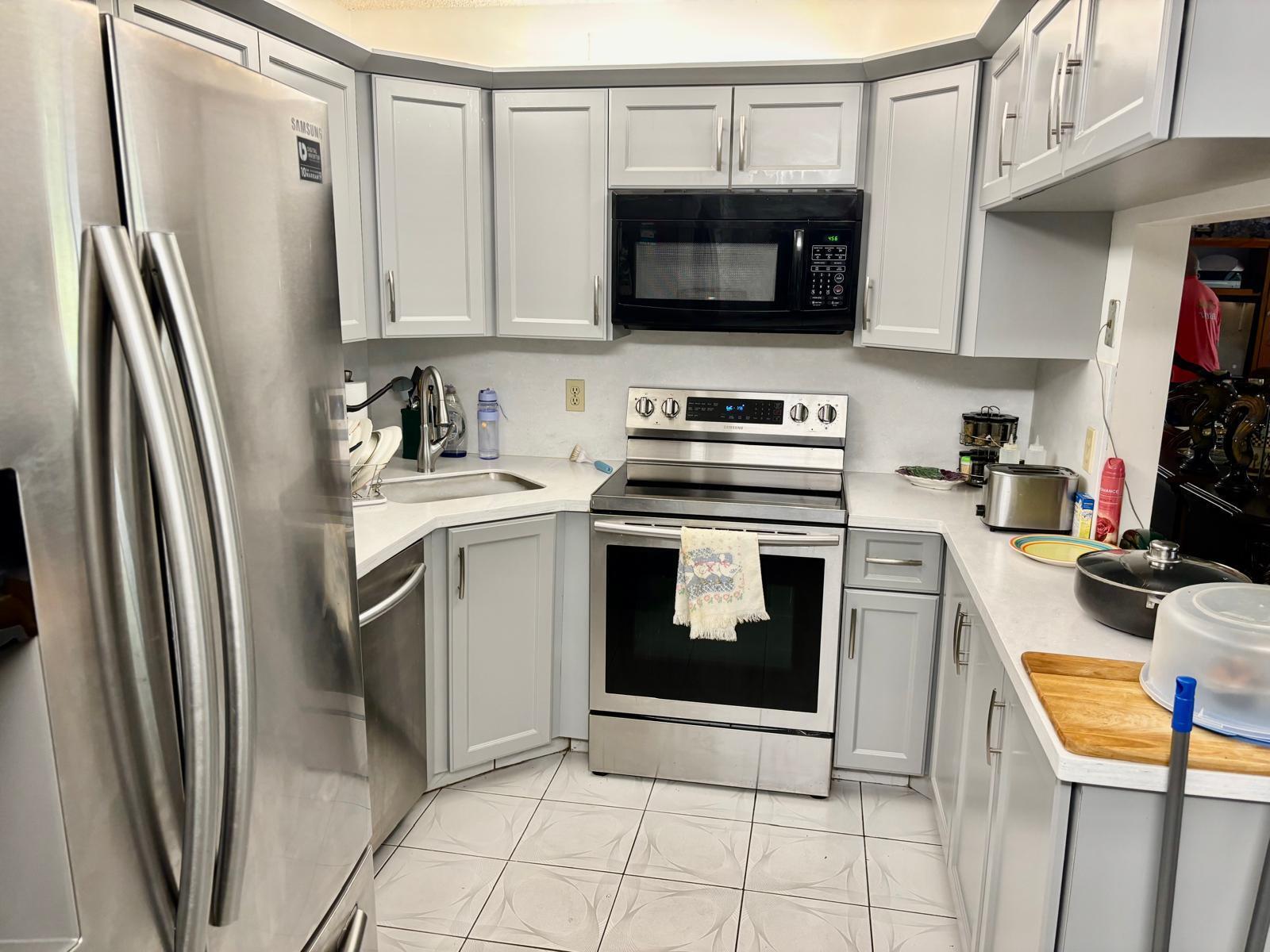 A kitchen with light gray cabinets, stainless steel appliances, and white countertops — 503 Shady Pine Way # A1, FL 33415, FL