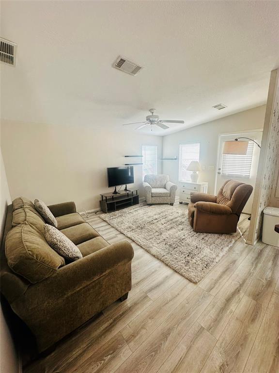 A living room features light wood-look flooring, a beige sofa, two armchairs, and a rug — 2305 BAY DRIVE, BRADENTON, FL