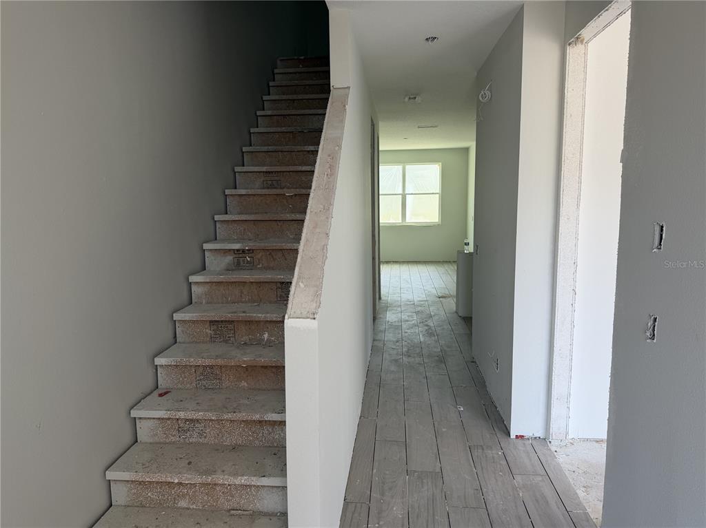 An unfinished interior hallway features a staircase with wooden treads and gray tile flooring — 7538 DEER VALLEY CIRCLE, TAMPA, FL