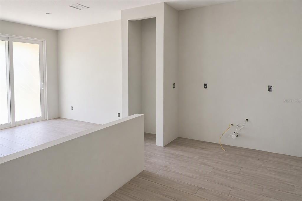 An interior view of a room with light wood-look flooring, white walls, and sliding doors — 7538 DEER VALLEY CIRCLE, TAMPA, FL