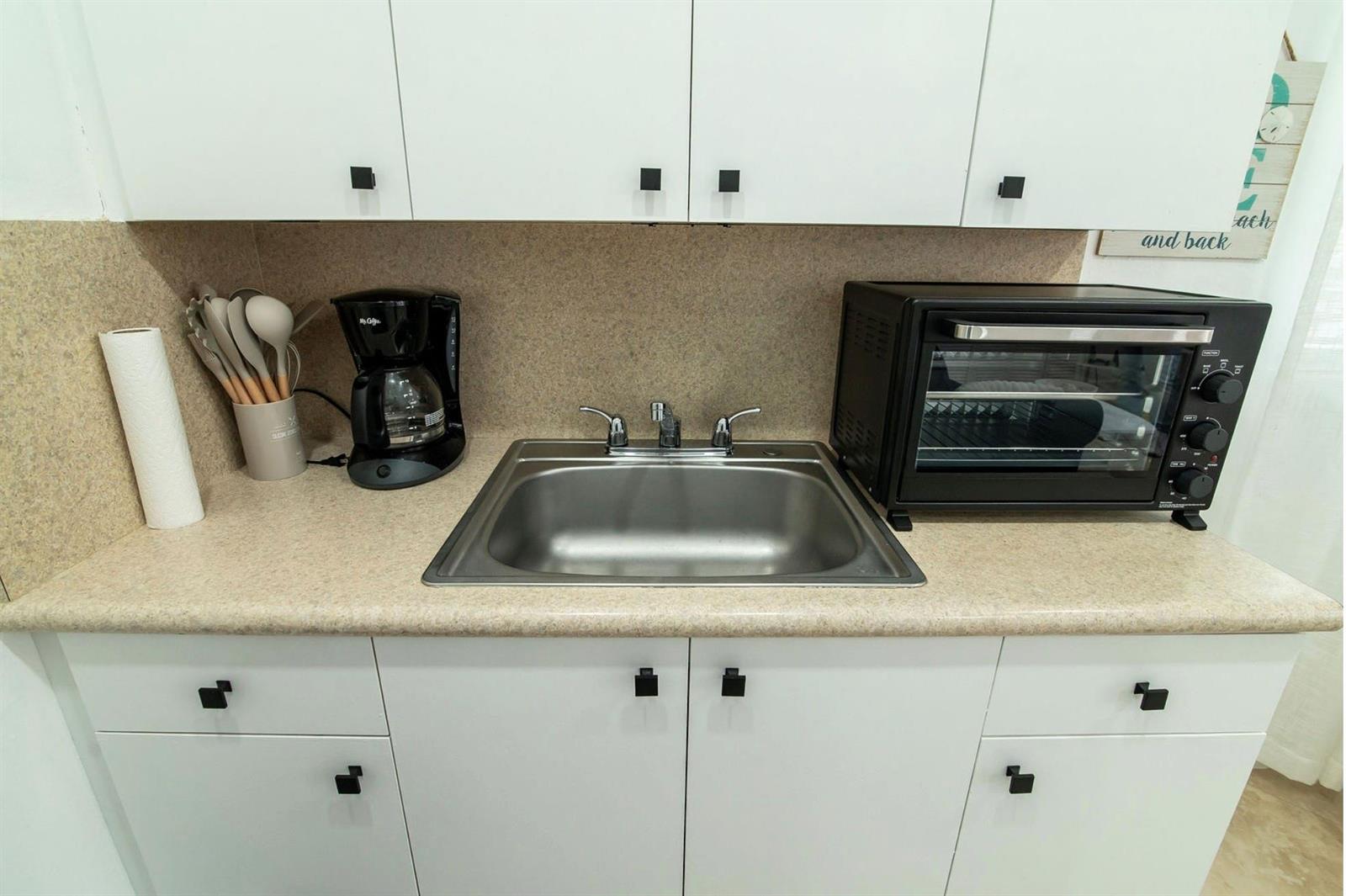 A kitchenette features white cabinets, a stainless steel sink, a coffee maker, and a toaster oven — 3230 NE 13th Street # 203, Pompano Beach FL 33062, POMPANO BEACH, FL