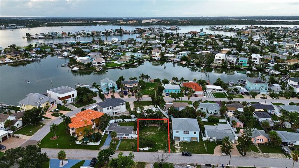 An aerial view shows a vacant residential lot outlined in red within a waterfront neighborhood — 14061 MIRAMAR AVENUE, MADEIRA BEACH, FL