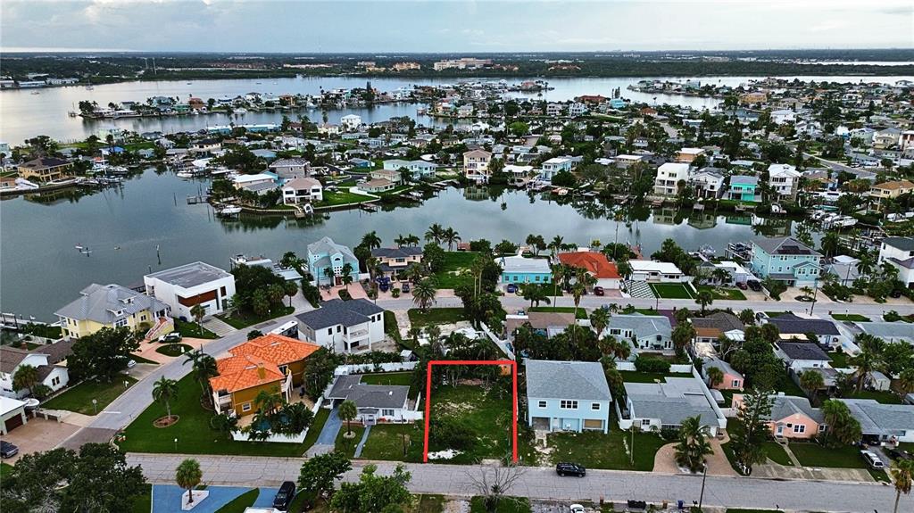 An aerial view shows a vacant, rectangular lot outlined in red within a coastal neighborhood — 14061 MIRAMAR AVENUE, MADEIRA BEACH, FL