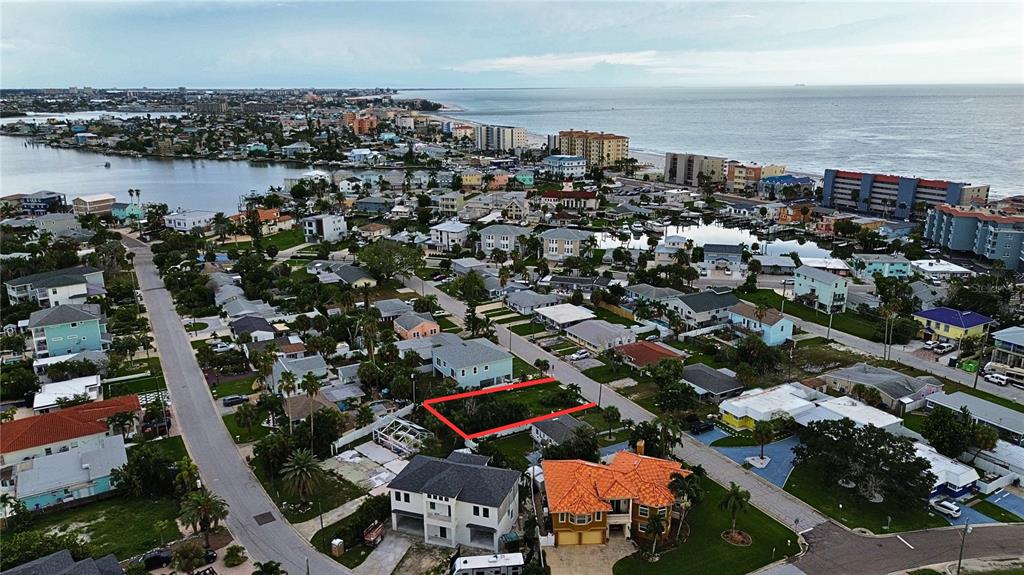 An aerial view shows a vacant residential lot outlined in red within a coastal neighborhood — 14061 MIRAMAR AVENUE, MADEIRA BEACH, FL