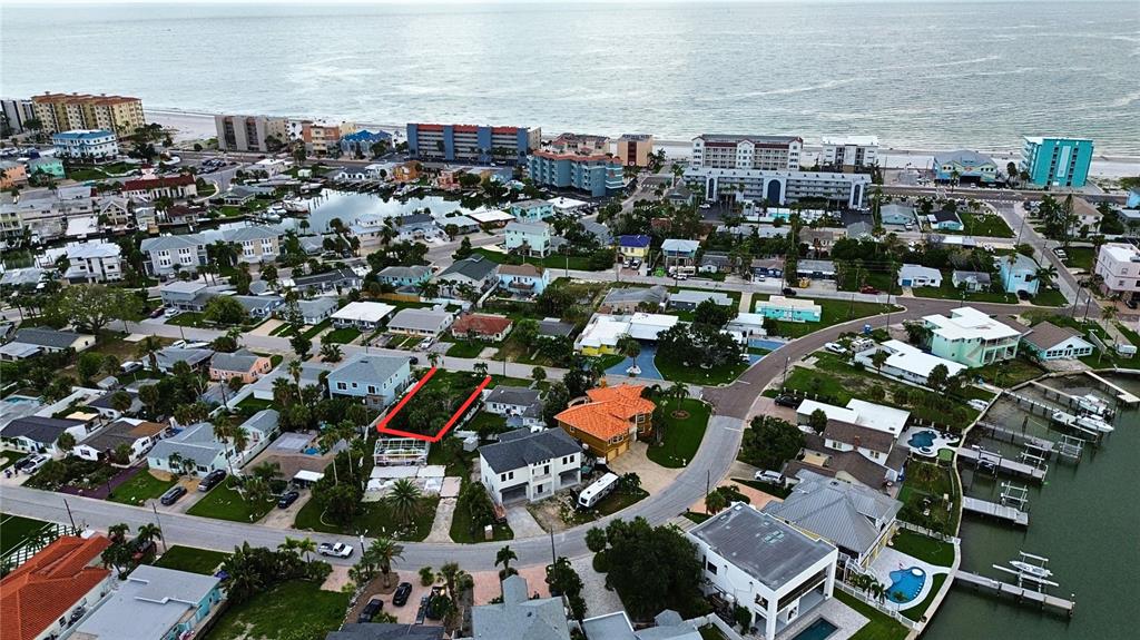 An aerial view shows a residential neighborhood with a highlighted vacant lot near the coast — 14061 MIRAMAR AVENUE, MADEIRA BEACH, FL