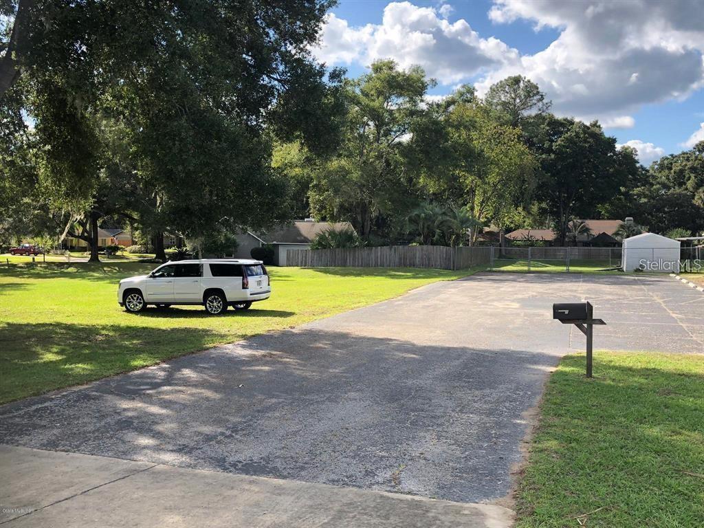 A white SUV is parked on a grassy lot next to a paved driveway — 1100 SE 58TH AVENUE UNIT A, OCALA, FL