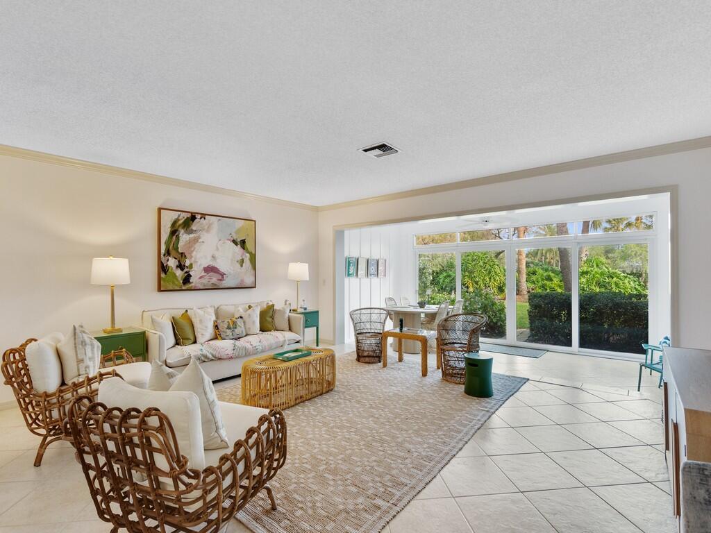 A bright living room features wicker chairs, a sofa, a coffee table, and sliding glass doors — VERO BEACH, FL