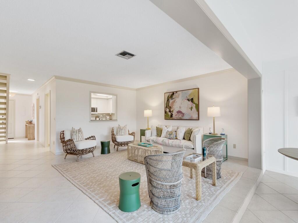 A living room features a neutral rug, wicker furniture, a sofa, and light-colored tile flooring — VERO BEACH, FL