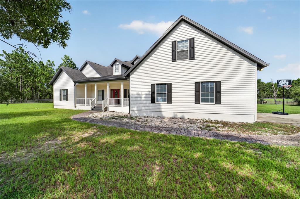 A two-story white house with black shutters, a front porch, and a stone walkway — 6351 SE 140 AVENUE, MORRISTON, FL