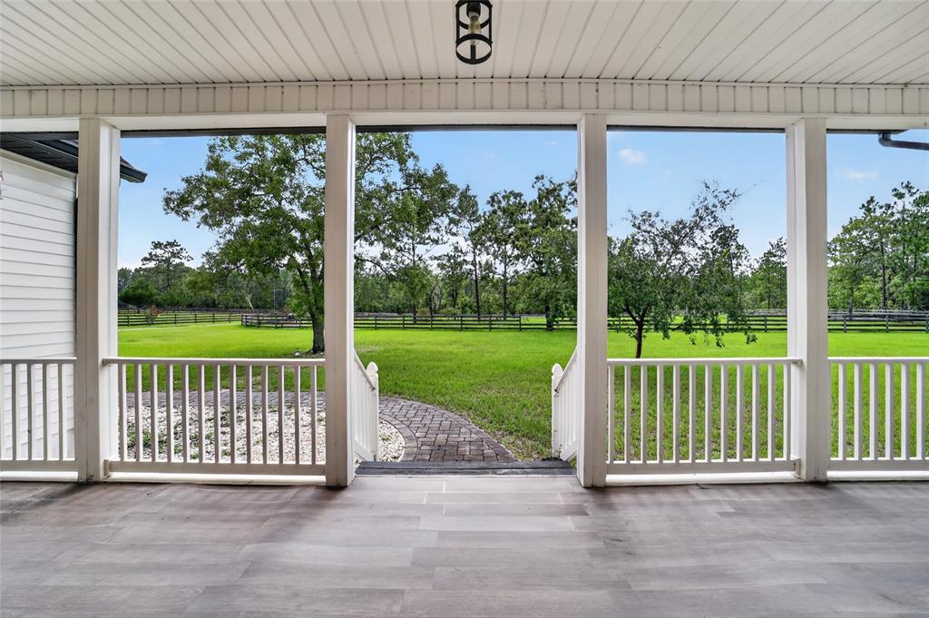 A covered porch with white railings overlooks a grassy yard and a brick walkway — 6351 SE 140 AVENUE, MORRISTON, FL
