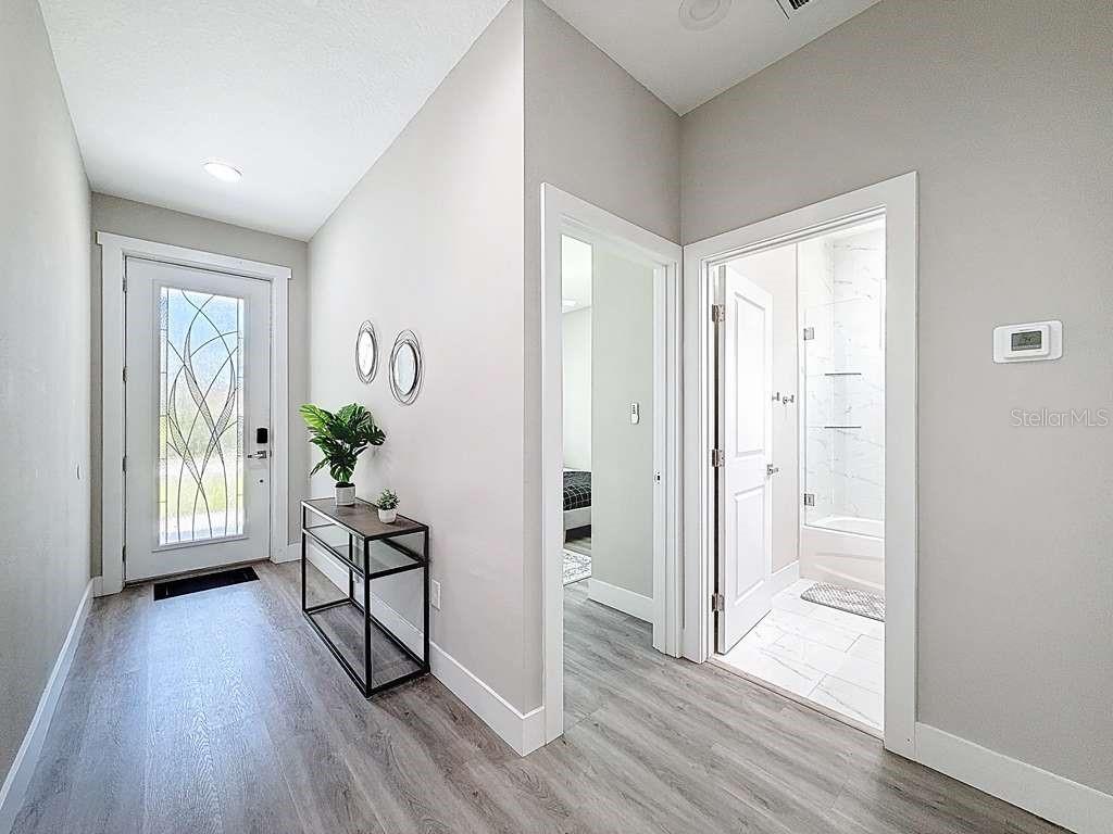 A bright entryway features light wood-look flooring, a glass-paneled front door, and two doorways — 1409 W WOOD STREET, TAMPA, FL