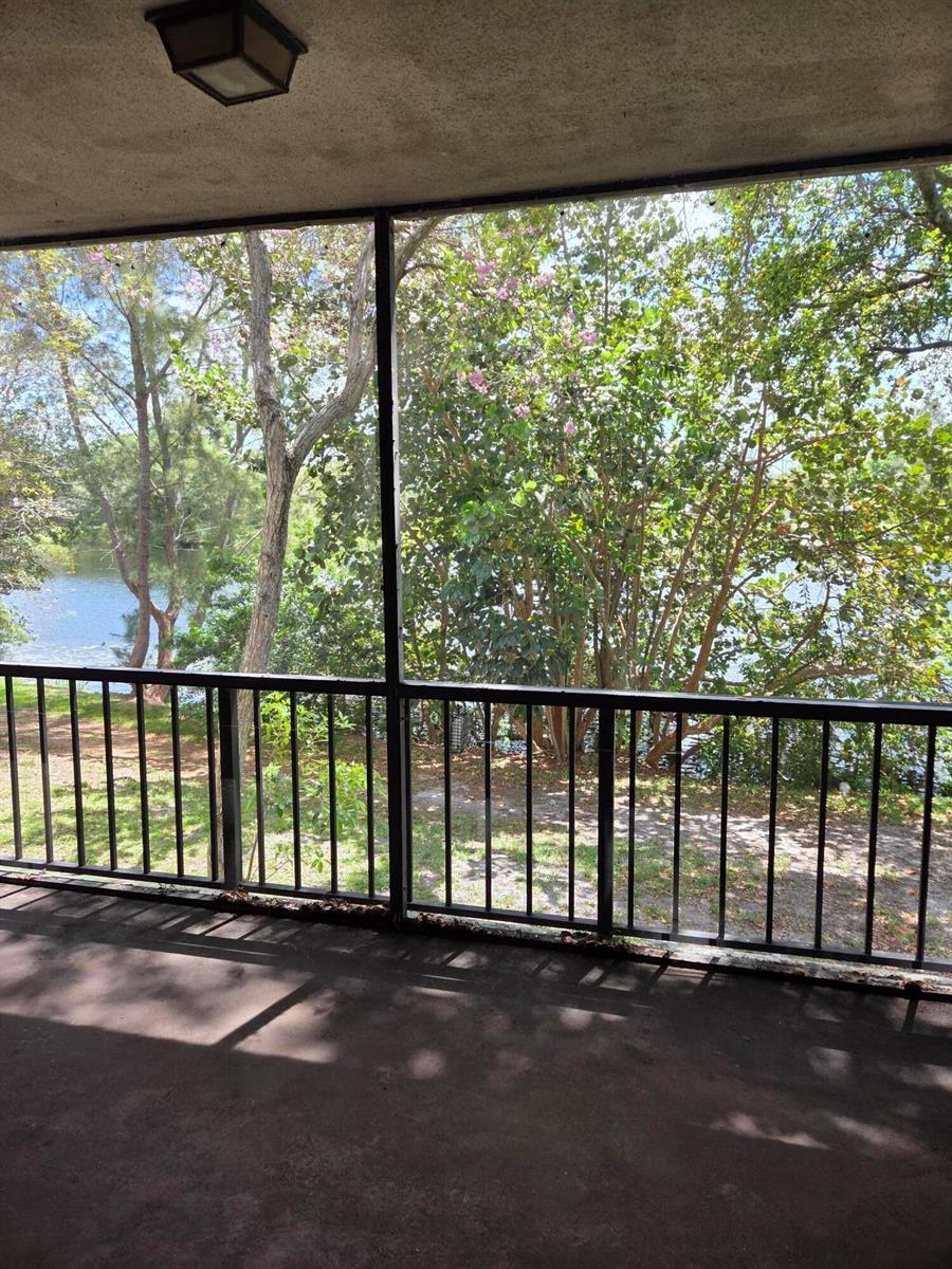 A screened-in porch with a metal railing overlooks a lake and surrounding trees — 3720 Inverrary Drive # 2b, Lauderhill FL 33319, LAUDERHILL, FL