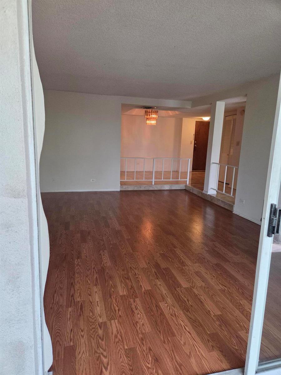 An interior view of a living room with wood-look flooring and a raised dining area — 3720 Inverrary Drive # 2b, Lauderhill FL 33319, LAUDERHILL, FL
