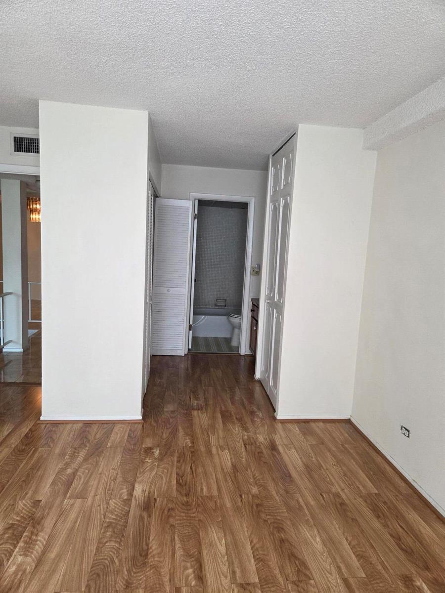 A room with wood-look flooring leads to a bathroom through an open doorway — 3720 Inverrary Drive # 2b, Lauderhill FL 33319, LAUDERHILL, FL
