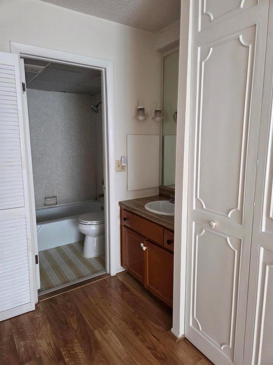 A bathroom features a wooden vanity, a mirror, and an adjacent room with a tub — 3720 Inverrary Drive # 2b, Lauderhill FL 33319, LAUDERHILL, FL