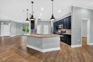 A kitchen with dark cabinets, a granite-topped island, and wood-look flooring — 1475 DALBORA ROAD, MERRITT ISLAND, FL