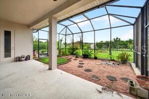 A screened-in patio features a concrete floor, gravel ground, and a view of the yard — 1475 DALBORA ROAD, MERRITT ISLAND, FL