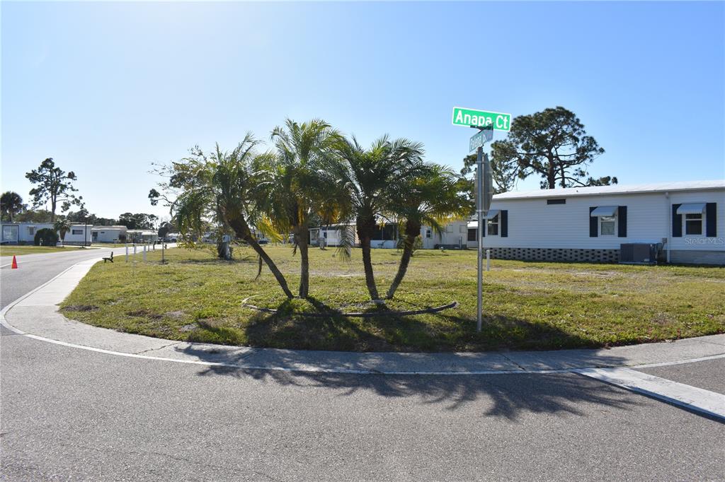 A vacant corner lot features a small cluster of palm trees and a street sign — 6805 ANAPA COURT, NORTH PORT, FL