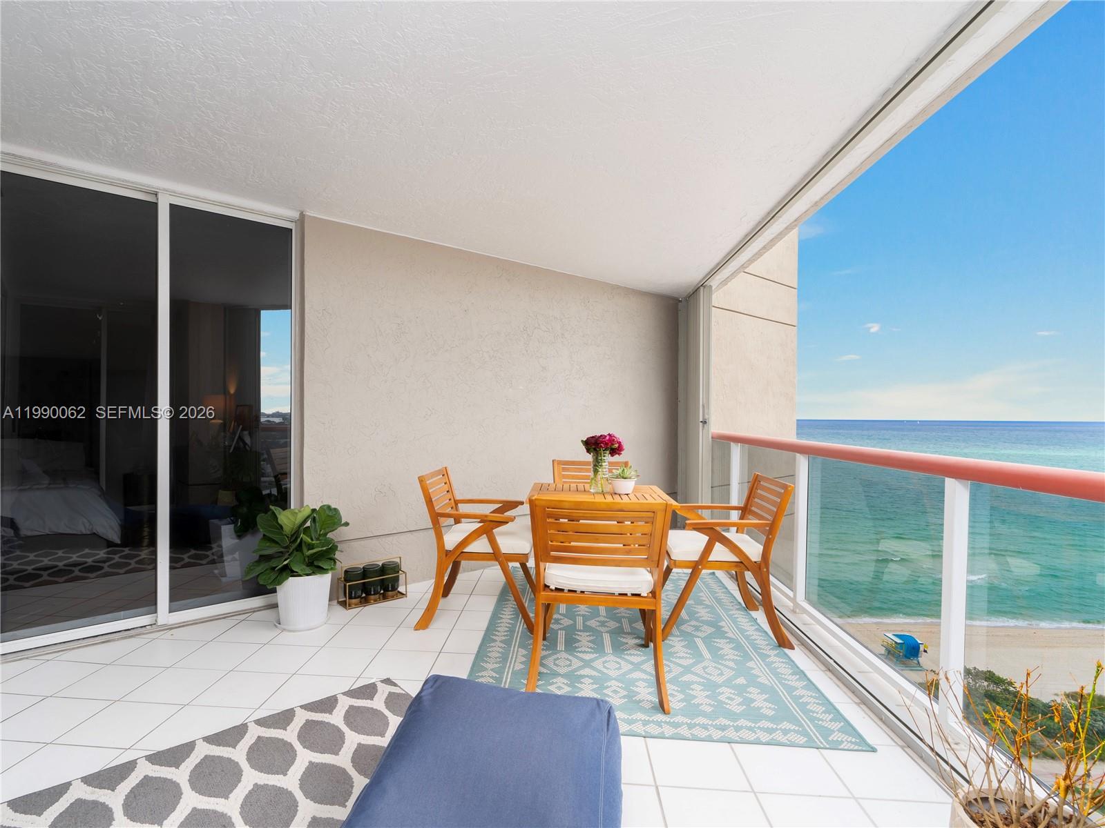 A balcony with a dining set, a patterned rug, and an ocean view — 6767 Collins Ave # 1704, Miami Beach FL 33141, MIAMI BEACH, FL