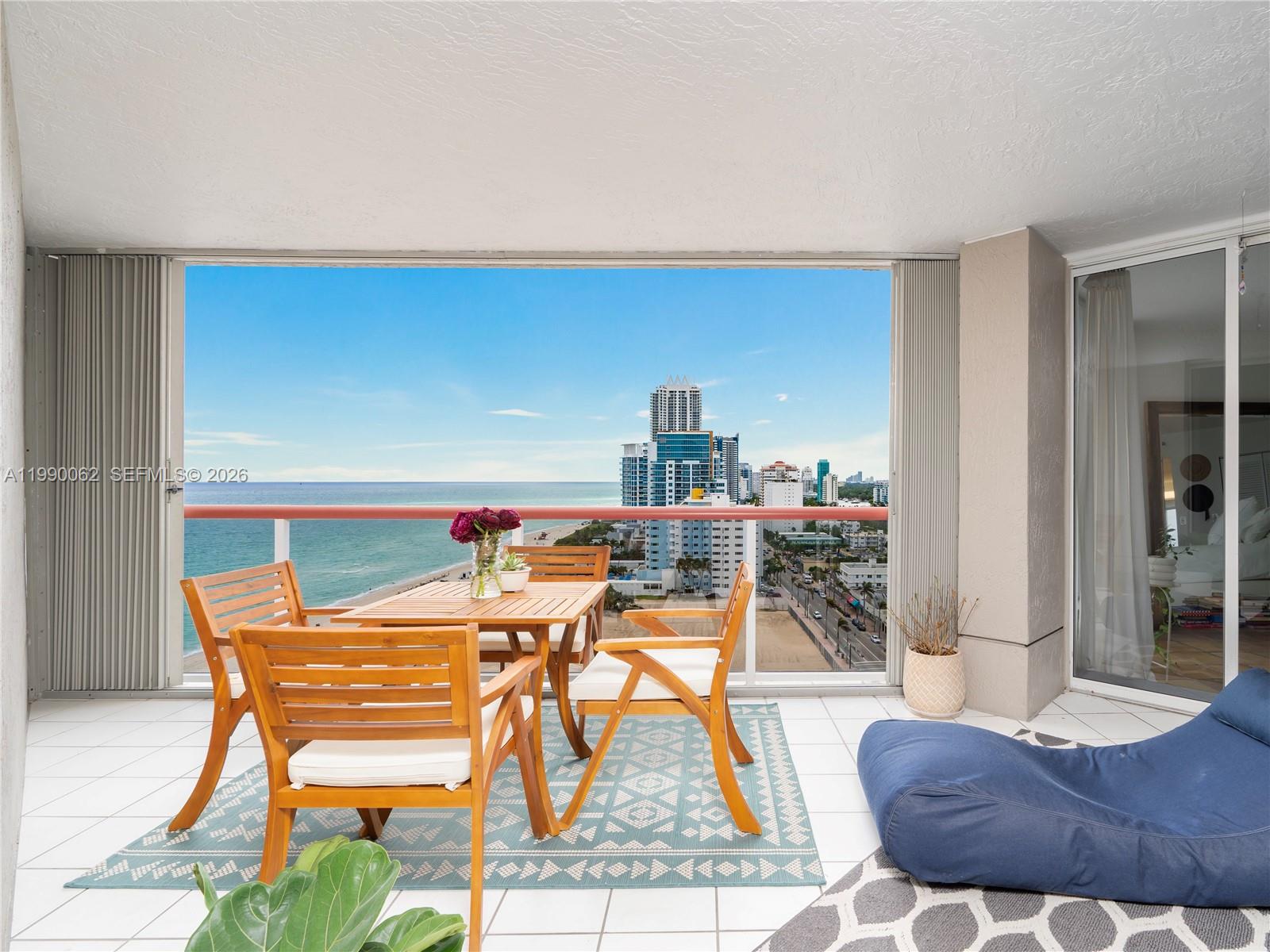 A balcony features a wooden dining set, a blue beanbag chair, and ocean views — 6767 Collins Ave # 1704, Miami Beach FL 33141, MIAMI BEACH, FL