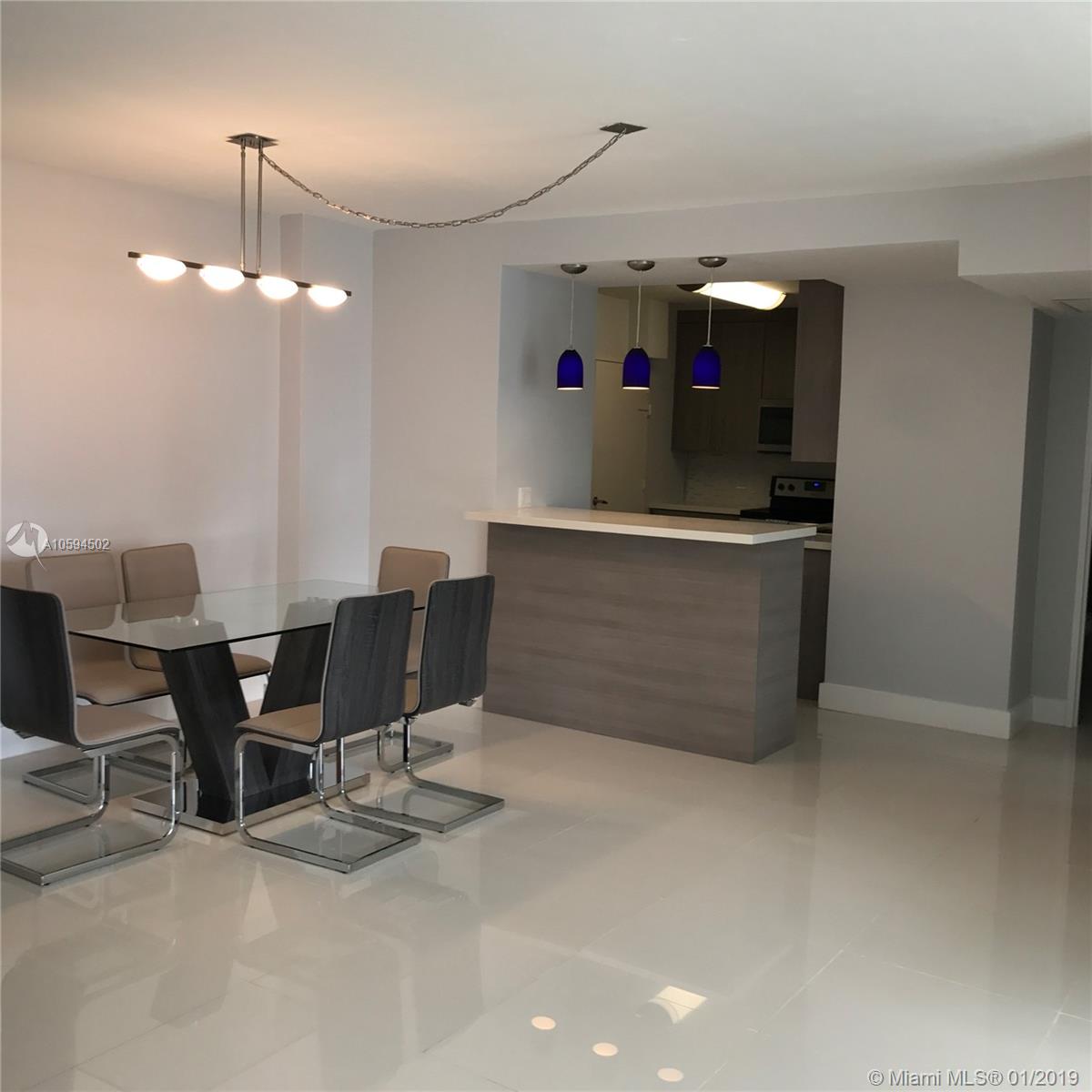 A dining area with a glass table and a kitchen breakfast bar with blue pendant lights — 3801 S Ocean Dr # 10V, Hollywood FL 33019, HOLLYWOOD, FL