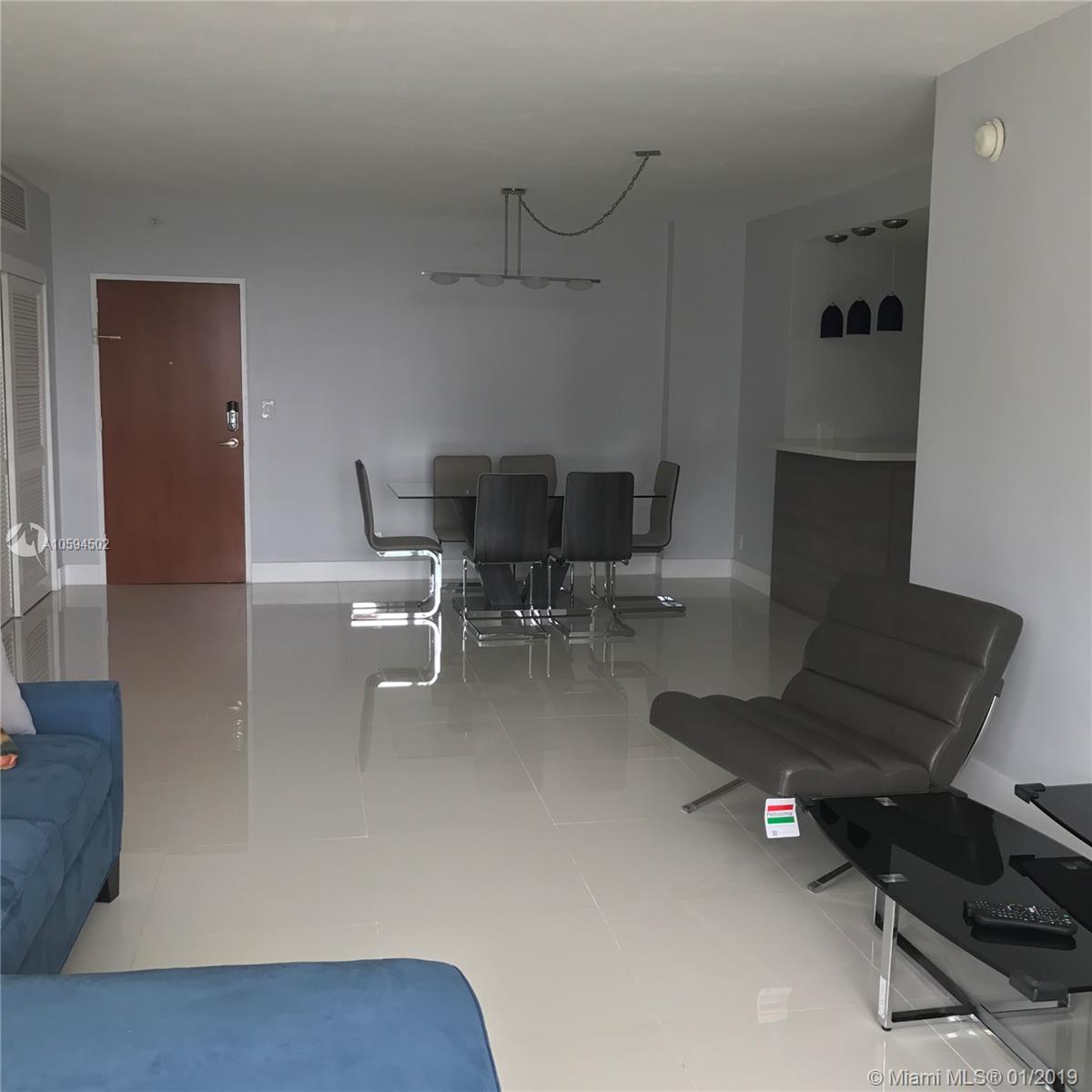 A living and dining area features light tile flooring, grey walls, and modern furniture — 3801 S Ocean Dr # 10V, Hollywood FL 33019, HOLLYWOOD, FL