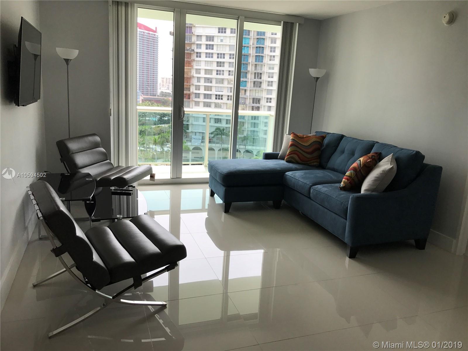 A living room features a blue sectional sofa, two black chairs, and floor-to-ceiling windows — 3801 S Ocean Dr # 10V, Hollywood FL 33019, HOLLYWOOD, FL