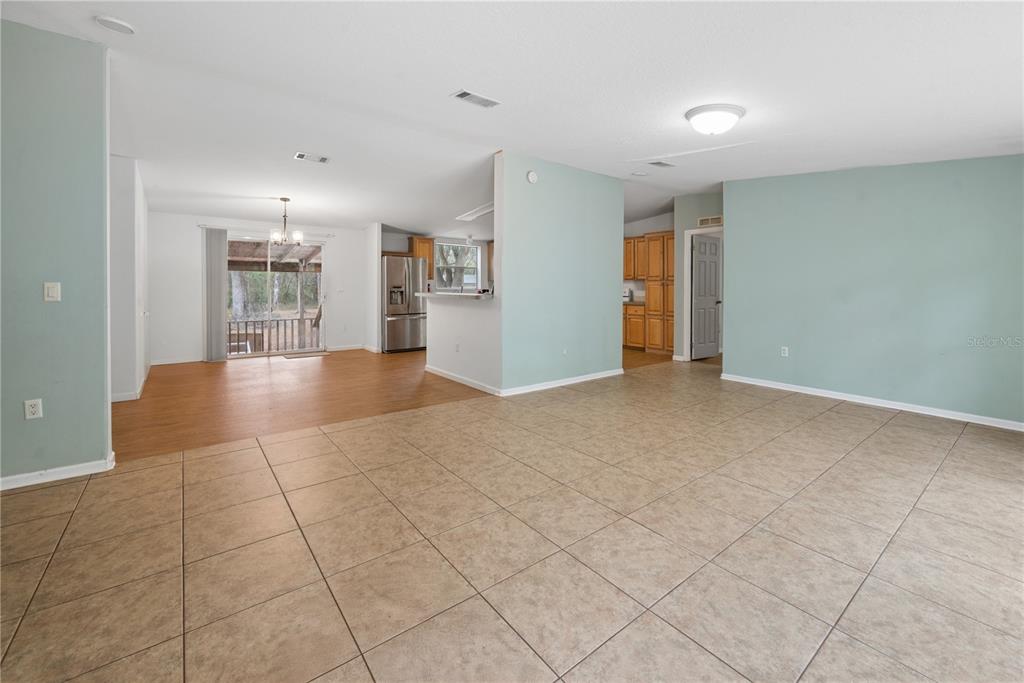 An open-concept living area features light blue walls, tile flooring, and an adjacent kitchen — 19514 N COUNTY ROAD 225, GAINESVILLE, FL