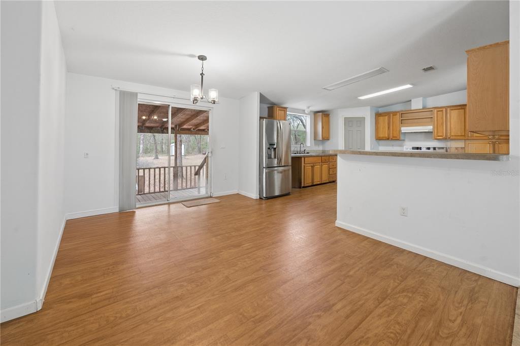 An open-concept kitchen and dining area features wood-look flooring, light-colored walls, and a sliding door — 19514 N COUNTY ROAD 225, GAINESVILLE, FL