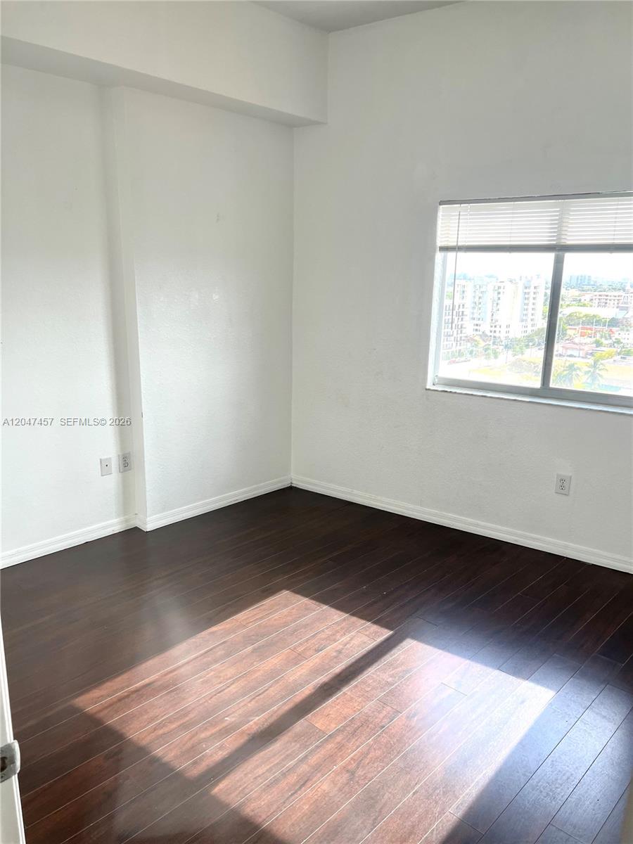 An empty bedroom features white walls, dark wood-look flooring, and a window with blinds — 36 NW 6th Ave # 1, Miami FL 33128, MIAMI, FL
