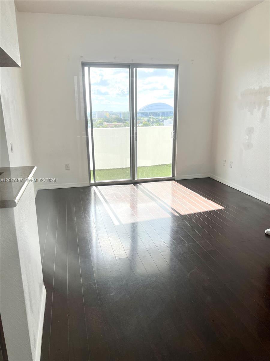 This room features dark wood flooring, white walls, and a sliding glass door to a balcony — 36 NW 6th Ave # 1, Miami FL 33128, MIAMI, FL