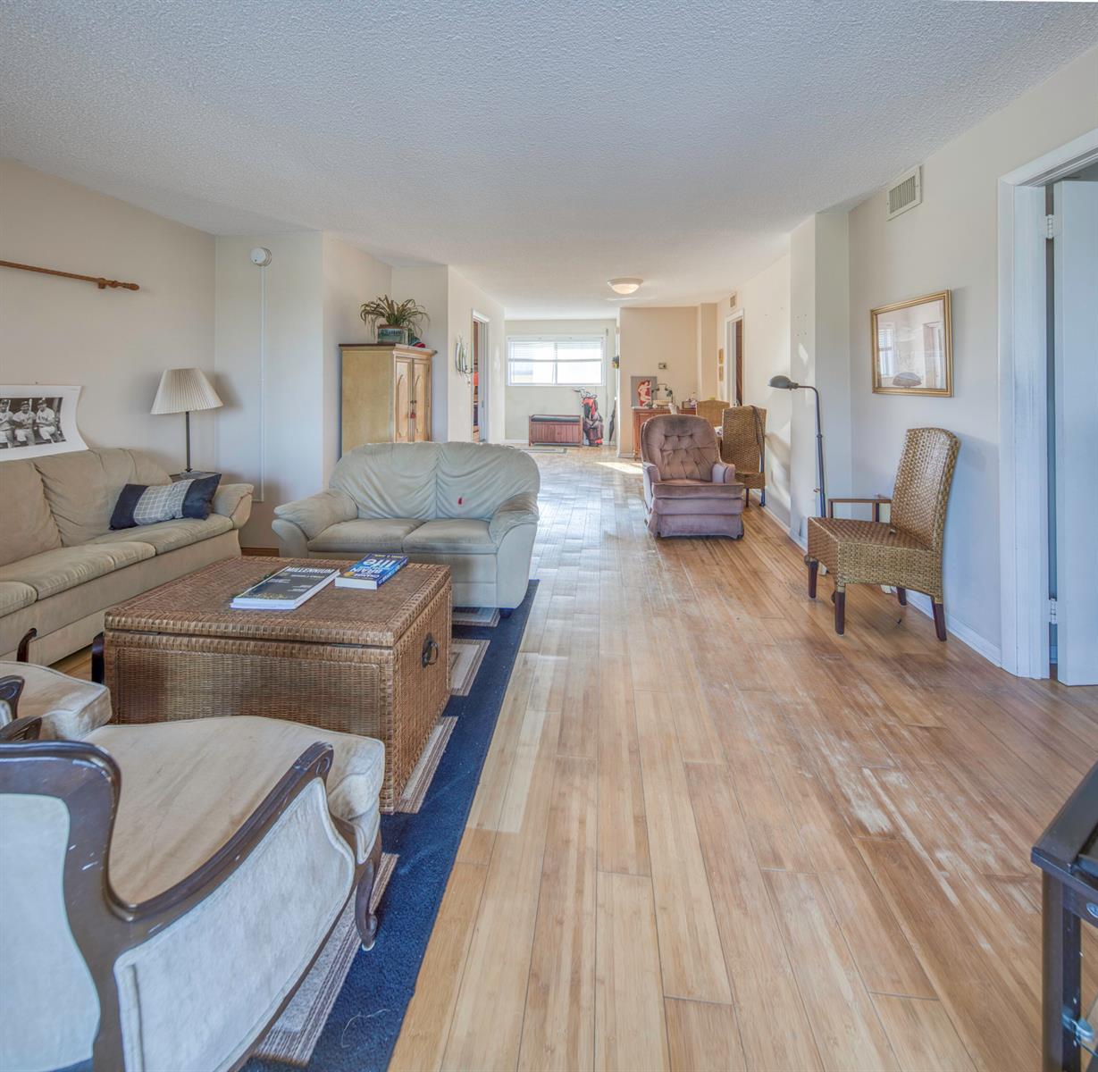 A living room features light wood flooring, a blue area rug, and various seating arrangements — 1 N Golfview Road # 205, FL 33460, FL