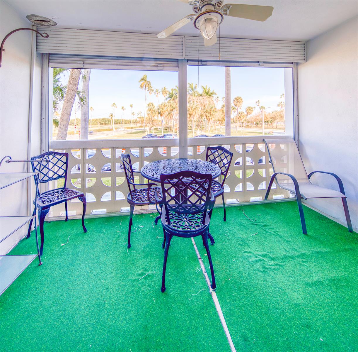 A screened-in balcony features green outdoor carpeting, a metal dining set, and palm tree views — 1 N Golfview Road # 205, FL 33460, FL