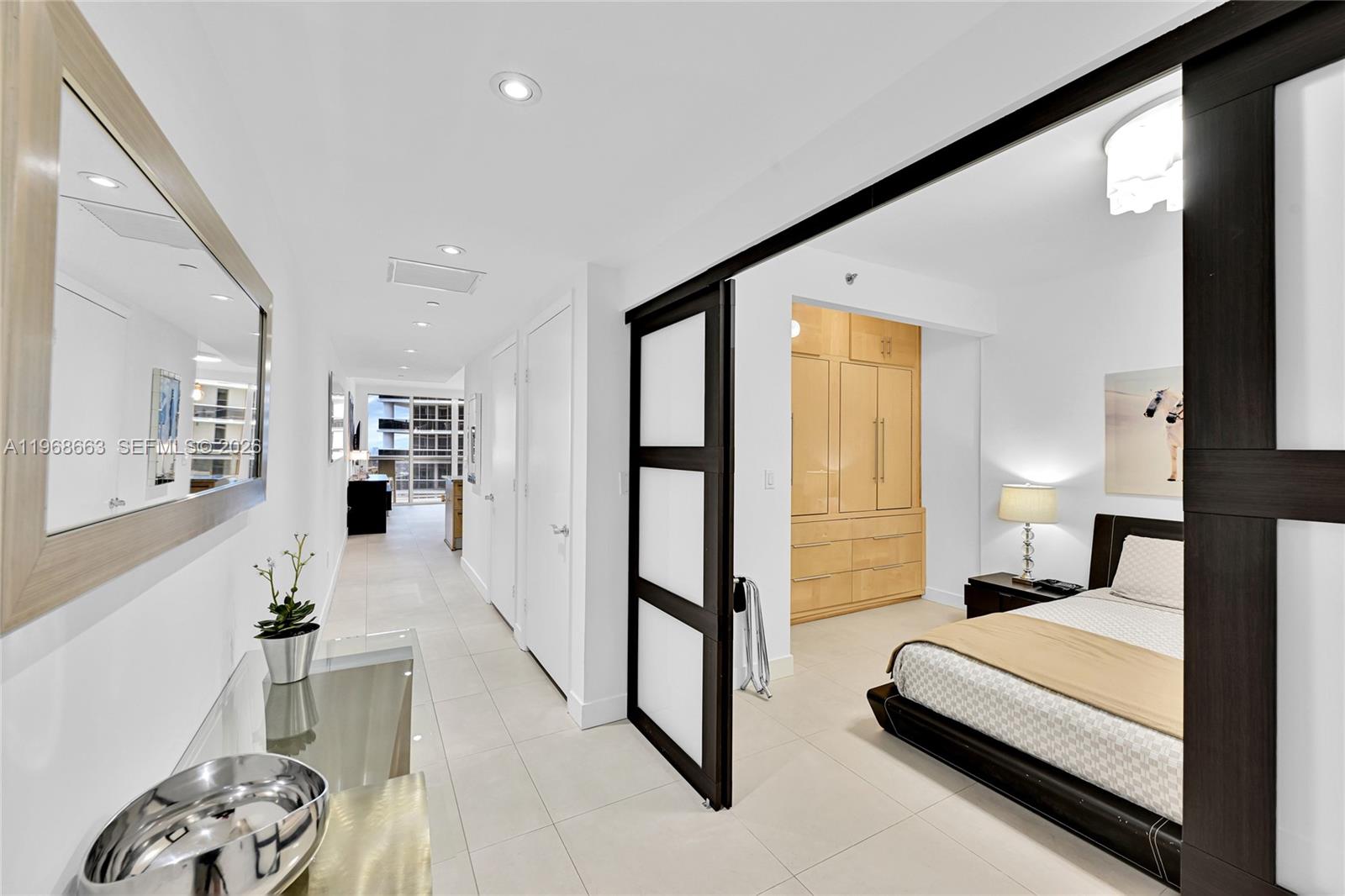 A bedroom with a sliding glass door opens into a hallway with light tile flooring — 1830 S Ocean Dr # 4005, Hallandale Beach FL 33009, HALLANDALE BEACH, FL