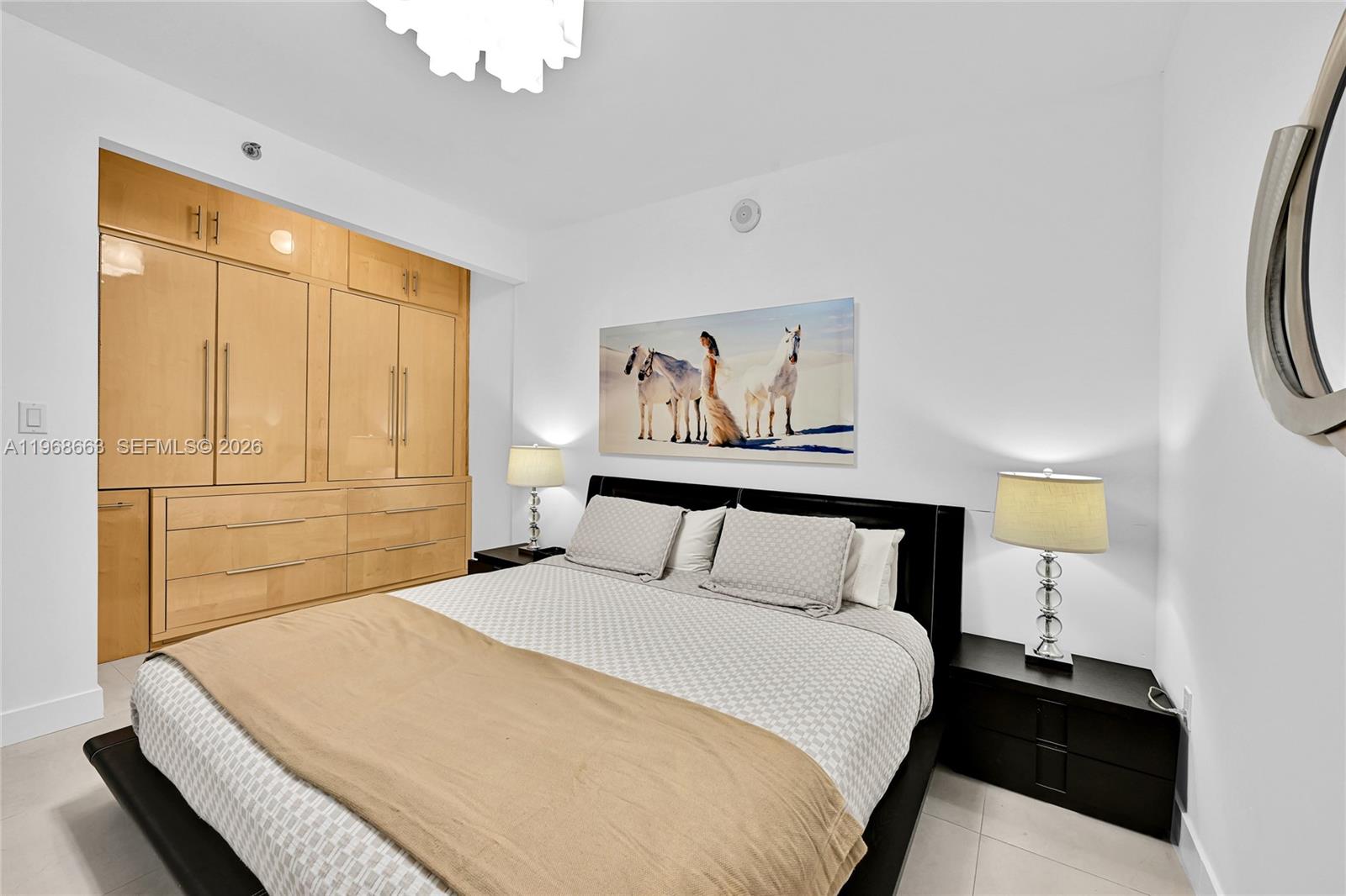 A bedroom features a bed with a patterned duvet, light wood cabinetry, and wall art — 1830 S Ocean Dr # 4005, Hallandale Beach FL 33009, HALLANDALE BEACH, FL