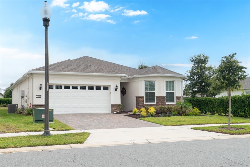A single-story house with a two-car garage, stone accents, and a paved driveway — 15139 CANOPY COVER DRIVE, WINTER GARDEN, FL