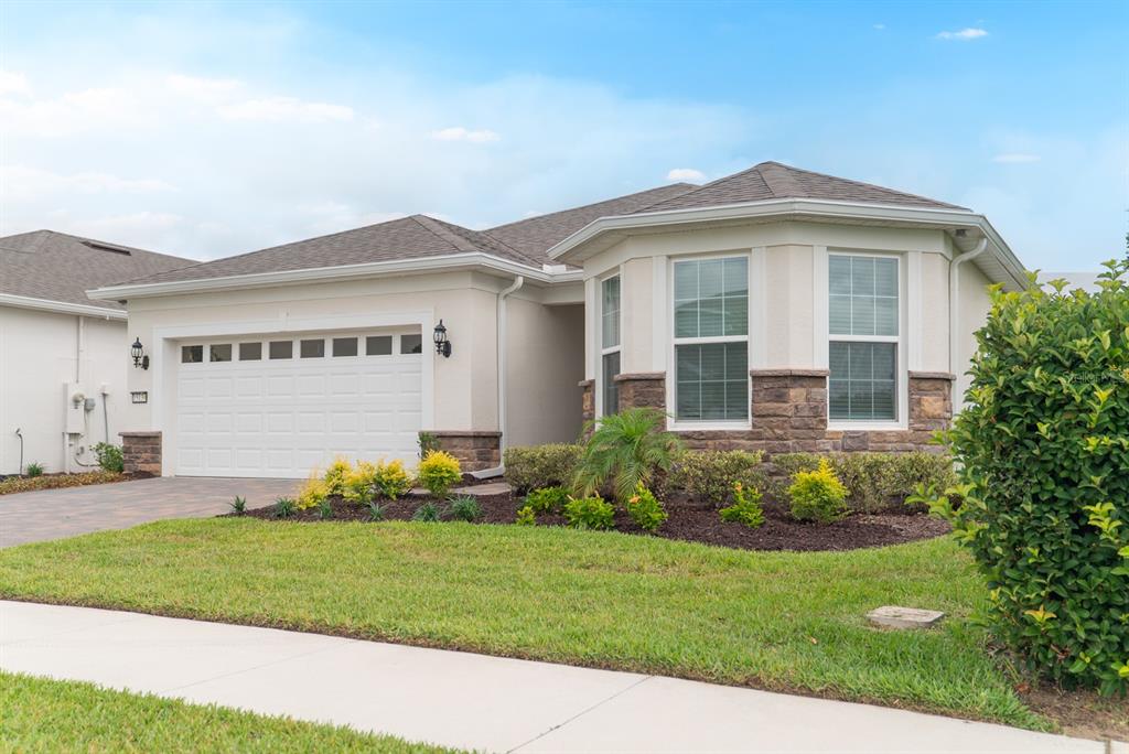A single-story house with a white stucco exterior, stone accents, and a two-car garage — 15139 CANOPY COVER DRIVE, WINTER GARDEN, FL
