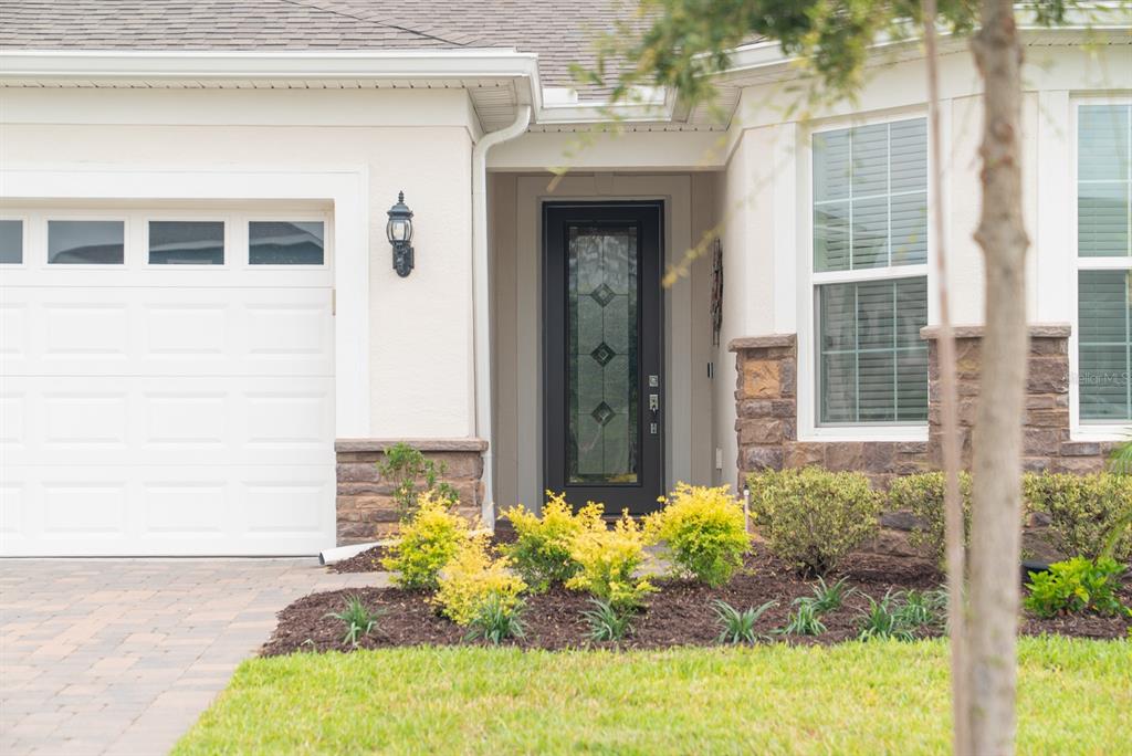 The exterior of a house features a garage, a dark front door, and stone accents — 15139 CANOPY COVER DRIVE, WINTER GARDEN, FL