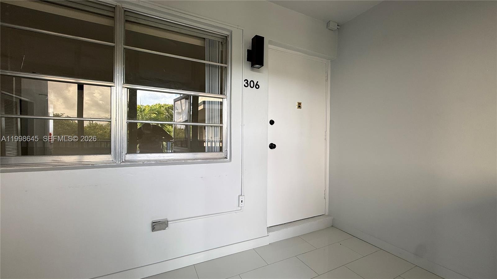 A white door labeled 306 sits next to a window on a tiled walkway — 1943 Monroe St # 306A, Hollywood FL 33020, HOLLYWOOD, FL