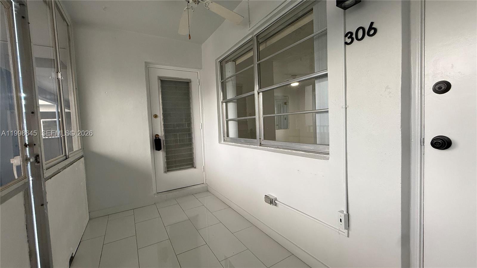 A white-walled entryway features tiled flooring, a glass-paneled door, and a windowed wall — 1943 Monroe St # 306A, Hollywood FL 33020, HOLLYWOOD, FL