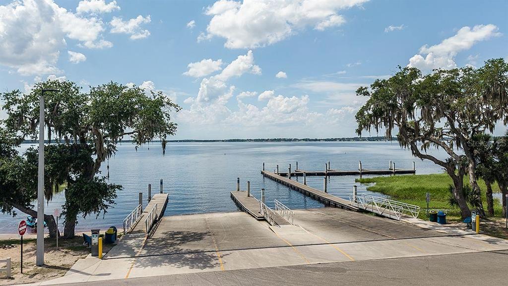 A concrete boat ramp leads into a lake with two wooden docks and large trees — 804 FORMOSA STREET, LAKE PLACID, FL