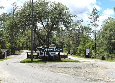 A sign for Leisure Lakes stands at the entrance of a tree-lined residential road — 804 FORMOSA STREET, LAKE PLACID, FL