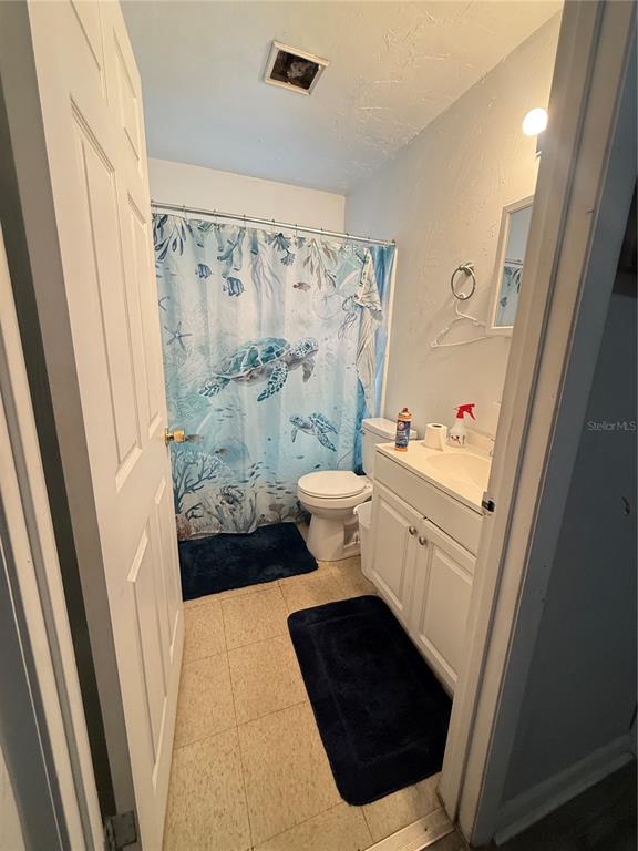 A bathroom features a white vanity, a toilet, and a sea turtle-themed shower curtain — 615 SW 11TH LANE UNIT A, GAINESVILLE, FL