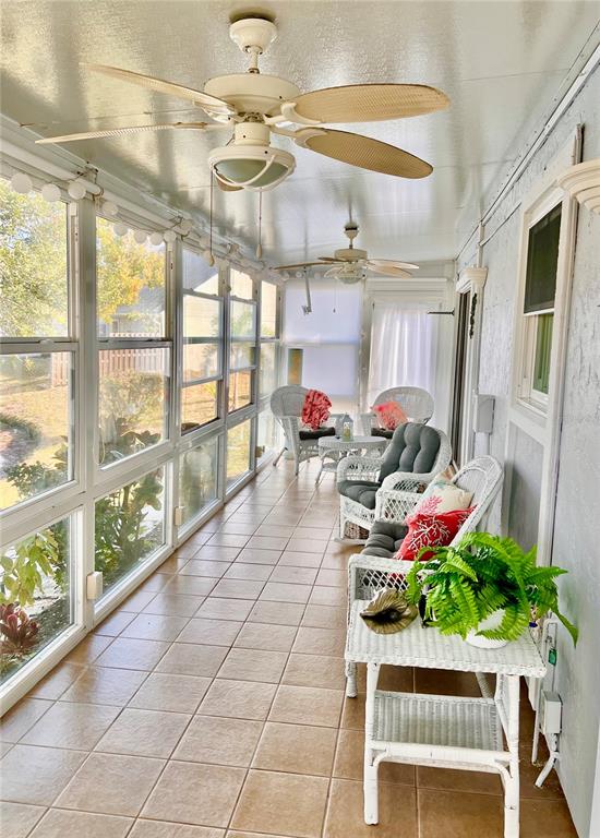 A sunroom features two white wicker chairs and a matching table overlooking a lake — 7801 ONTARIO STREET CIRCLE, SARASOTA, FL