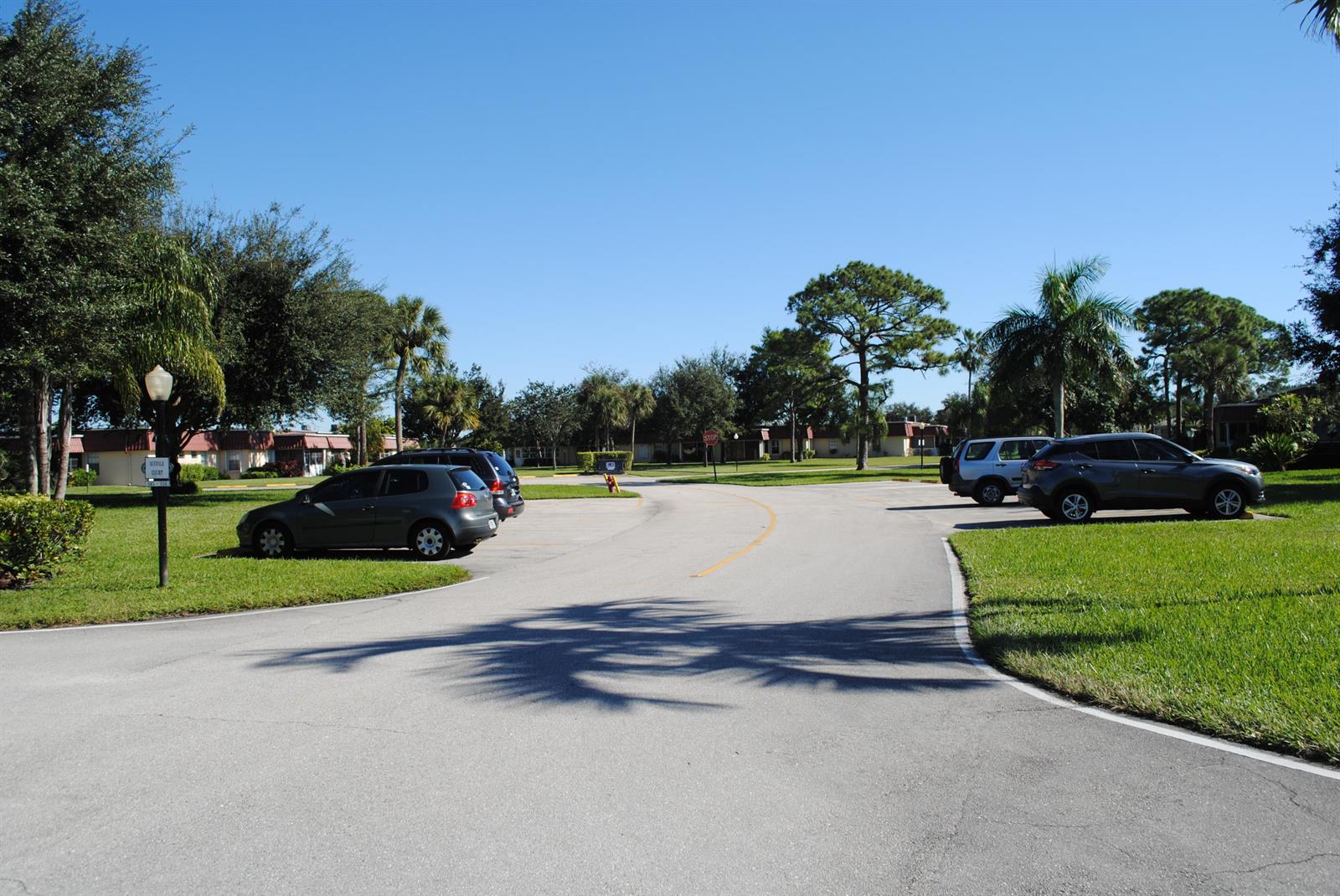 A paved parking lot with several cars parked in front of residential buildings and trees — 815 Salem Lane, Lake Worth FL 33467, LAKE WORTH, FL