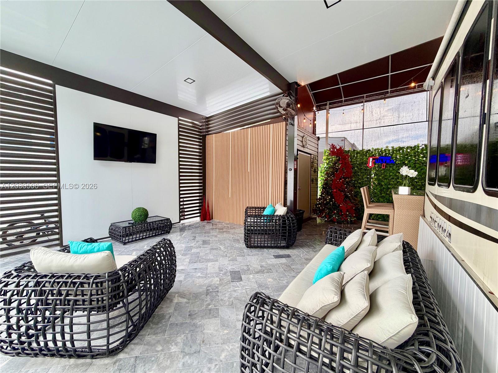 An outdoor patio features wicker furniture, a wall-mounted television, and a parked recreational vehicle — 325 Calusa Street #409, Key Largo FL 33037, KEY LARGO, FL