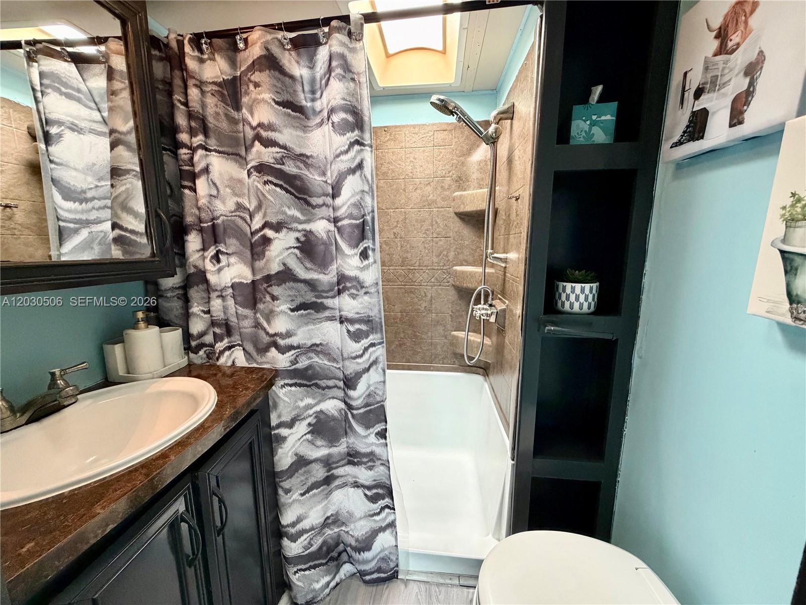 A bathroom features a vanity, a shower-tub combination with brown tile, and built-in shelving — 325 Calusa Street #409, Key Largo FL 33037, KEY LARGO, FL
