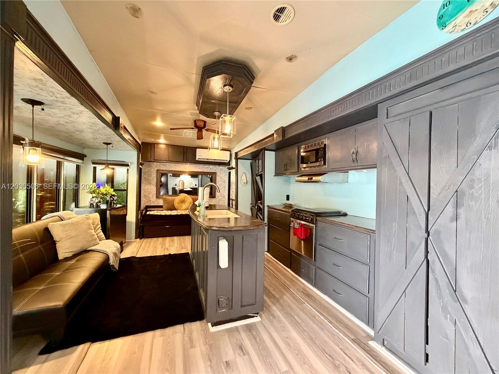 A kitchen and living area featuring dark cabinetry, a central island, and wood-look flooring — 325 Calusa Street #409, Key Largo FL 33037, KEY LARGO, FL