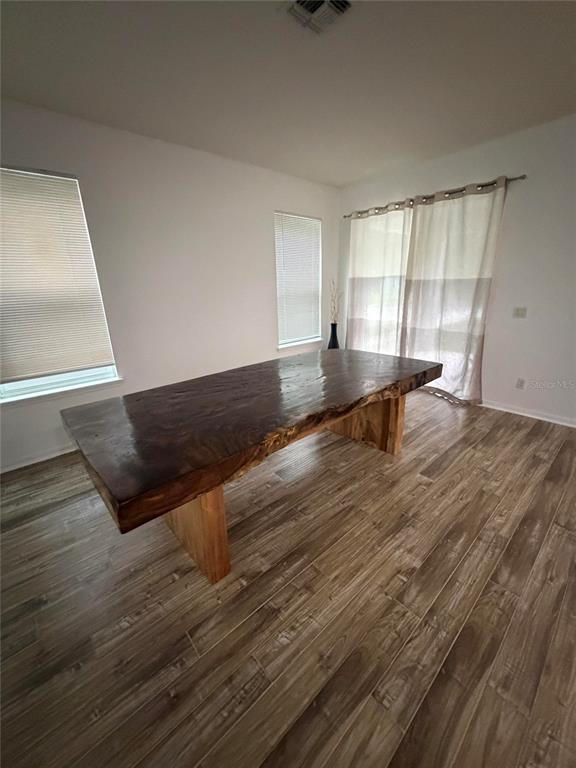 A dining room features a large live-edge wooden table on a wood-look tile floor — 7840 WINTER WREN STREET, WINTER GARDEN, FL