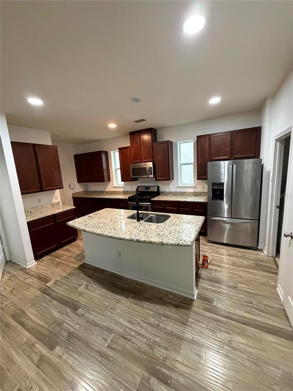 A kitchen features dark wood cabinets, granite countertops, a central island, and stainless steel appliances — 7840 WINTER WREN STREET, WINTER GARDEN, FL